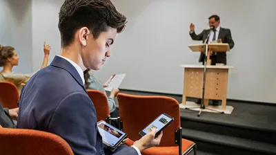 A brother responding to text messages during a congregation meeting.