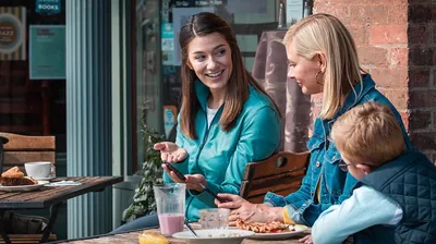 The sister is witnessing to the woman and her young son, using her phone.