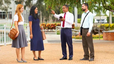 Two brothers and two sisters working together in the ministry. One of the brothers kindly directs the sisters to the area where they should preach.