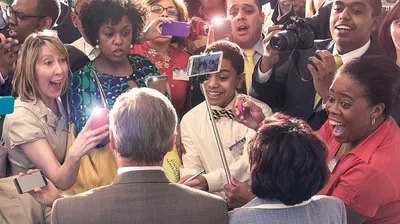A headquarters representative and his wife being mobbed by a crowd of brothers and sisters who want to take their picture.