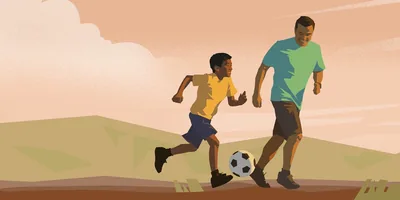 A man plays soccer with his son