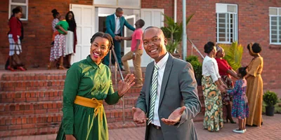A couple outside a Kingdom Hall extending a warm welcome.