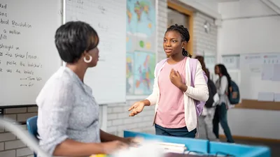 A young sister speaking respectfully to her schoolteacher.
