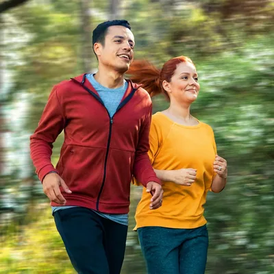 A couple jogging in a wooded area.
