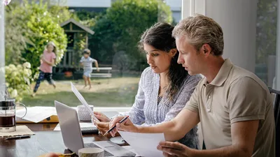 Parents discussing their finances while their children play in the backyard.