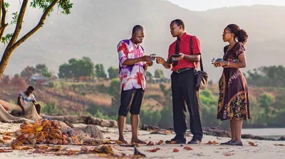 A couple in Sierra Leone give a meeting invitation to a local fisherman