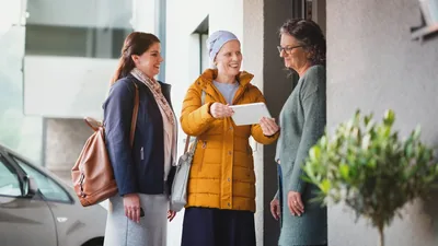A sister with a serious illness, joyfully working with her friend in the door-to-door ministry. She shares something on her tablet with a woman at her door.