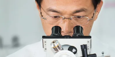 Yan-Der Hsuuw looks into a microscope