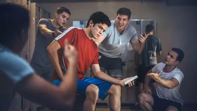 A young brother in a school locker room, being pressured by some of his schoolmates to use a smartphone to do something wrong. He contemplates whether to listen to them.