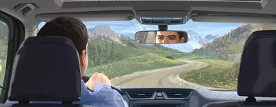 A man glancing at the rearview mirror while driving on a winding road.