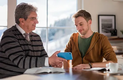 A brother using his phone to play a video for his Bible student.