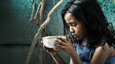 A starving young girl holding a bowl.