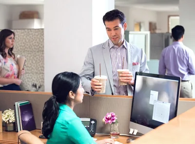 A man in a workplace brings a Christian woman something to drink